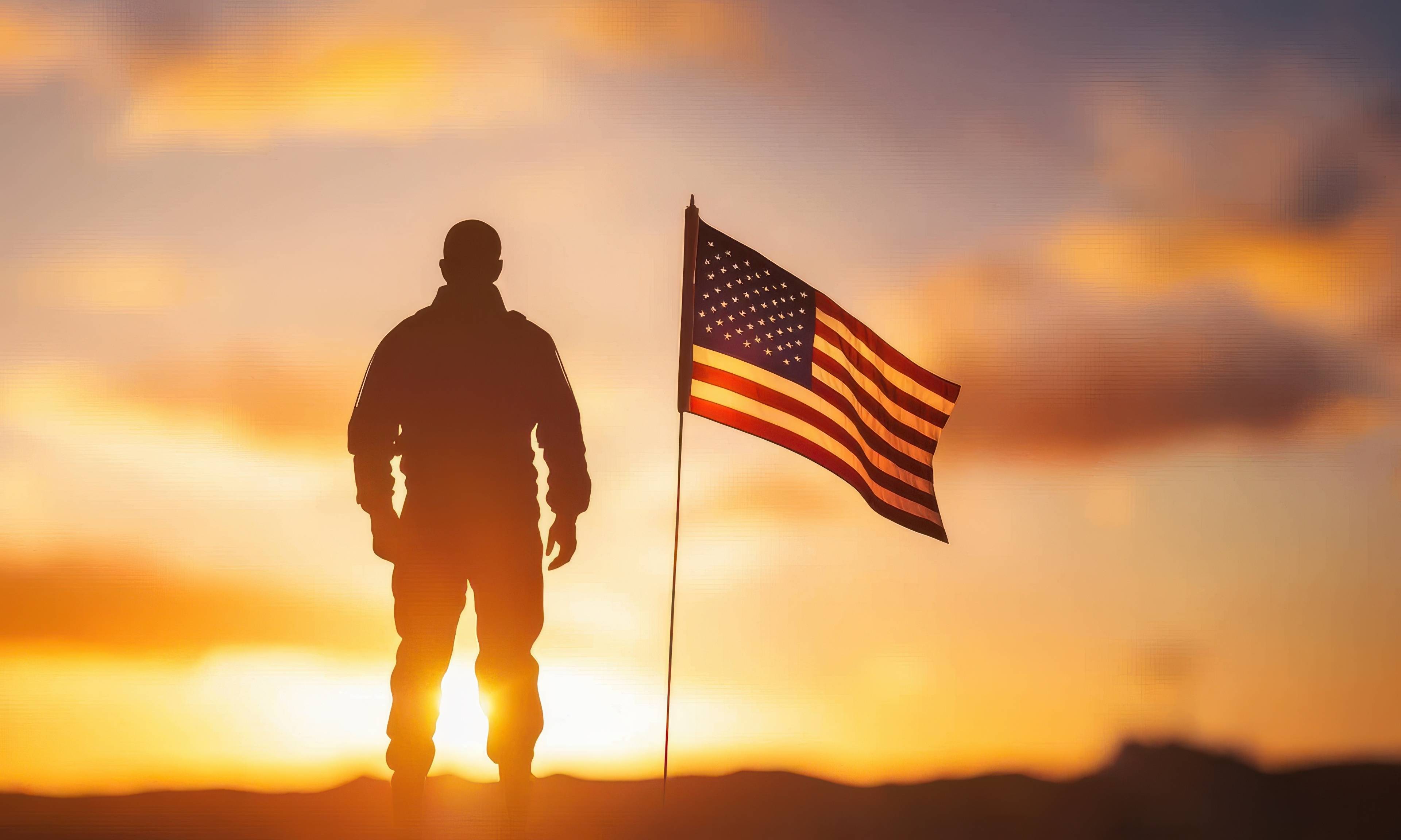Silhouette of a soldier standing next to an American flag against a golden sunset sky, symbolizing patriotism and military service.