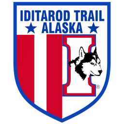 Iditarod Trail Alaska logo with shield design, red and blue colors, featuring a Husky dog head
