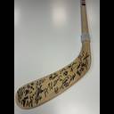 Wooden hockey stick blade with multiple autographs in black ink, against a light background.
