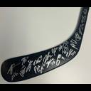 A black hockey stick with multiple silver autographs and signatures written along its blade and shaft, displayed against a white background.